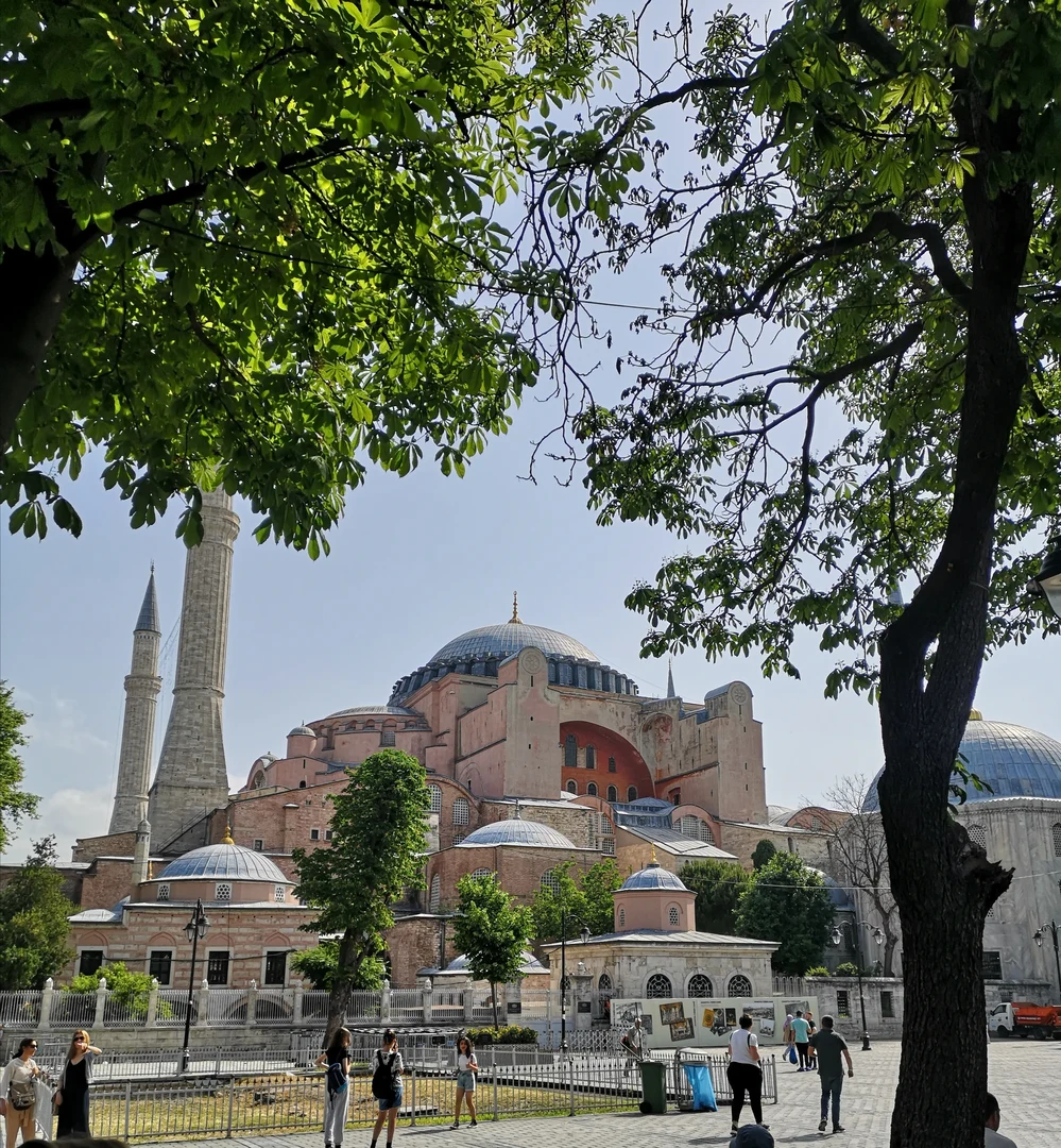 Eine Wissenschaftlerin und ein Wissenschaftler arbeiten hinter einer Glasfassade und mischen Chemikalien mit Großgeräten.