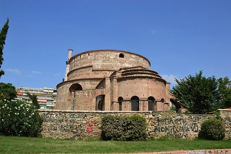 Eine Wissenschaftlerin und ein Wissenschaftler arbeiten hinter einer Glasfassade und mischen Chemikalien mit Großgeräten.