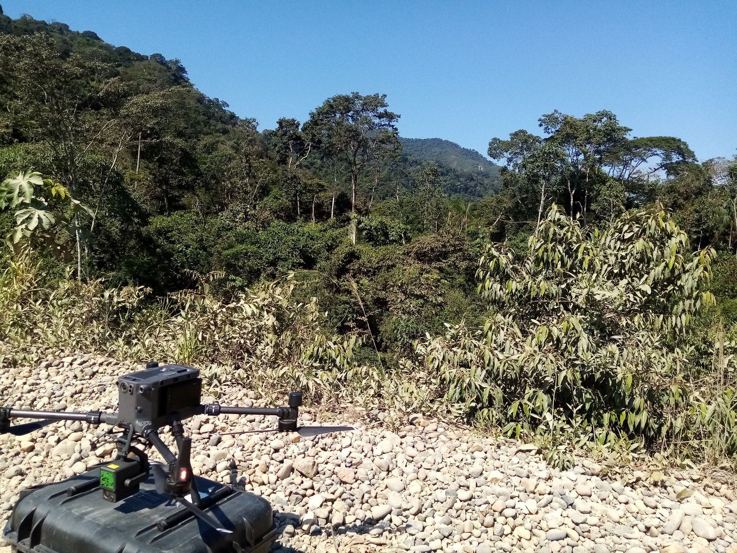 Preparing the drone to fly over the site known as "La Ruinas" in Macahua, located at the top of the mountain in the background of the image