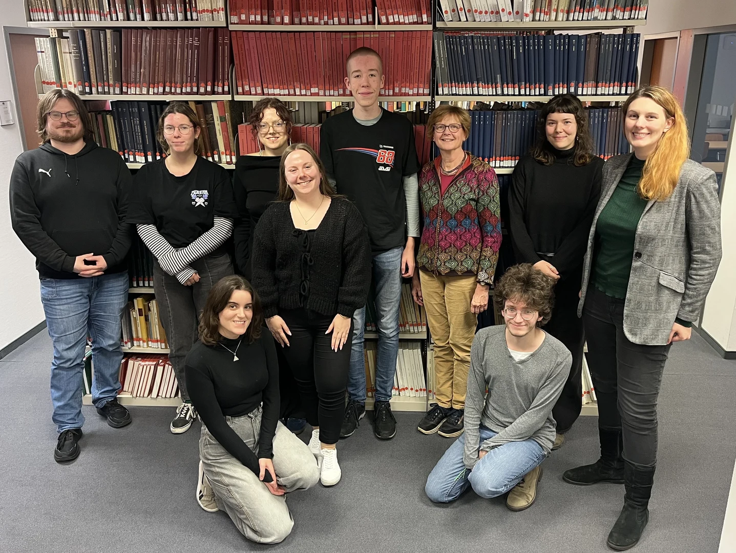 Eine Wissenschaftlerin und ein Wissenschaftler arbeiten hinter einer Glasfassade und mischen Chemikalien mit Großgeräten.