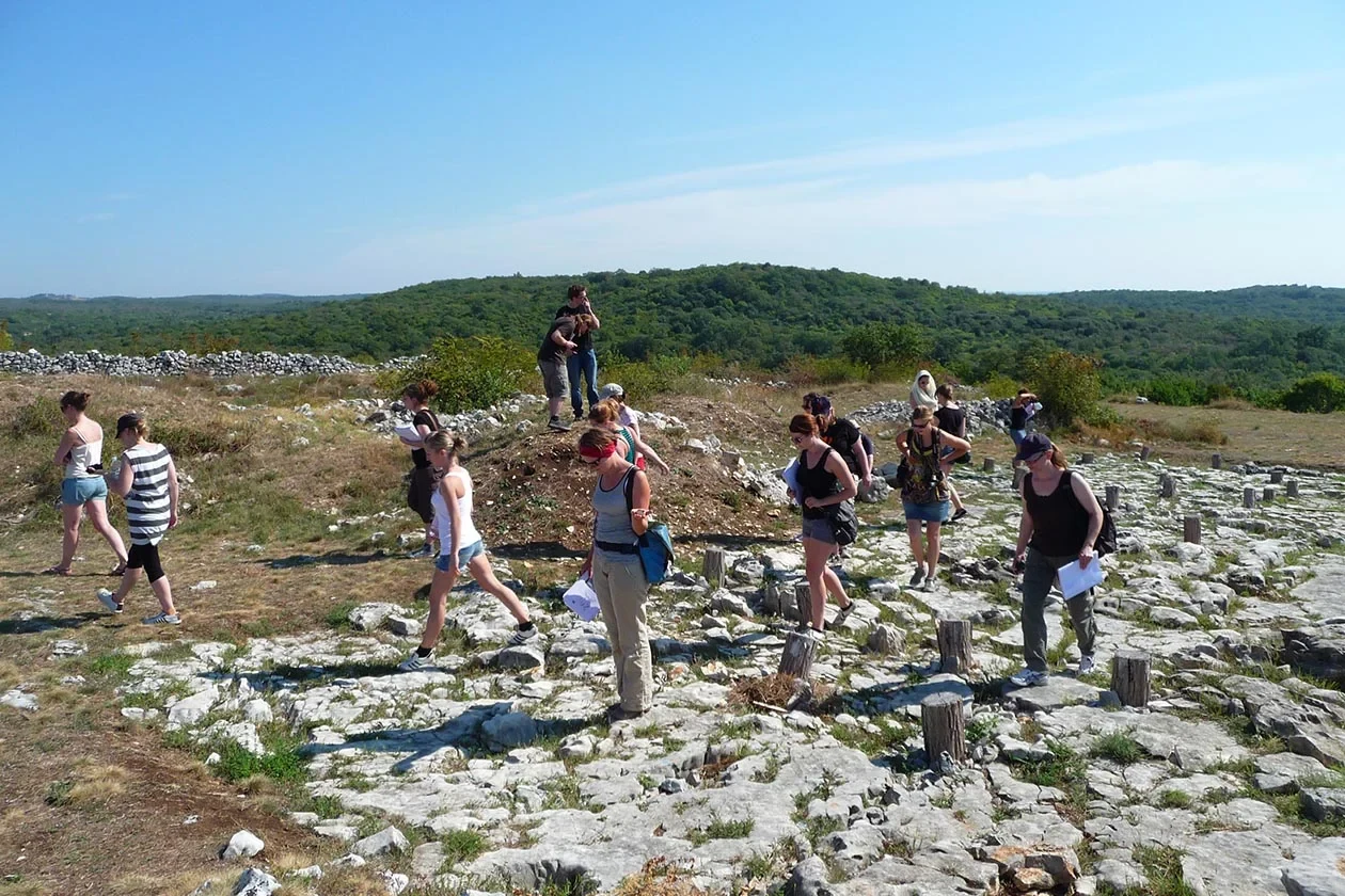 Eine Wissenschaftlerin und ein Wissenschaftler arbeiten hinter einer Glasfassade und mischen Chemikalien mit Großgeräten.