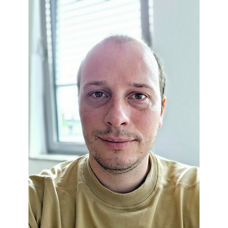 Eine Wissenschaftlerin und ein Wissenschaftler arbeiten hinter einer Glasfassade und mischen Chemikalien mit Großgeräten.