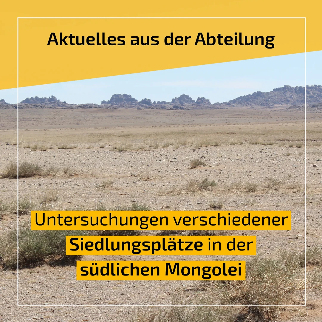 Eine Wissenschaftlerin und ein Wissenschaftler arbeiten hinter einer Glasfassade und mischen Chemikalien mit Großgeräten.