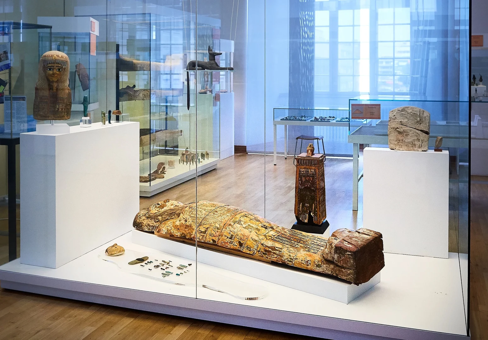 Eine Wissenschaftlerin und ein Wissenschaftler arbeiten hinter einer Glasfassade und mischen Chemikalien mit Großgeräten.