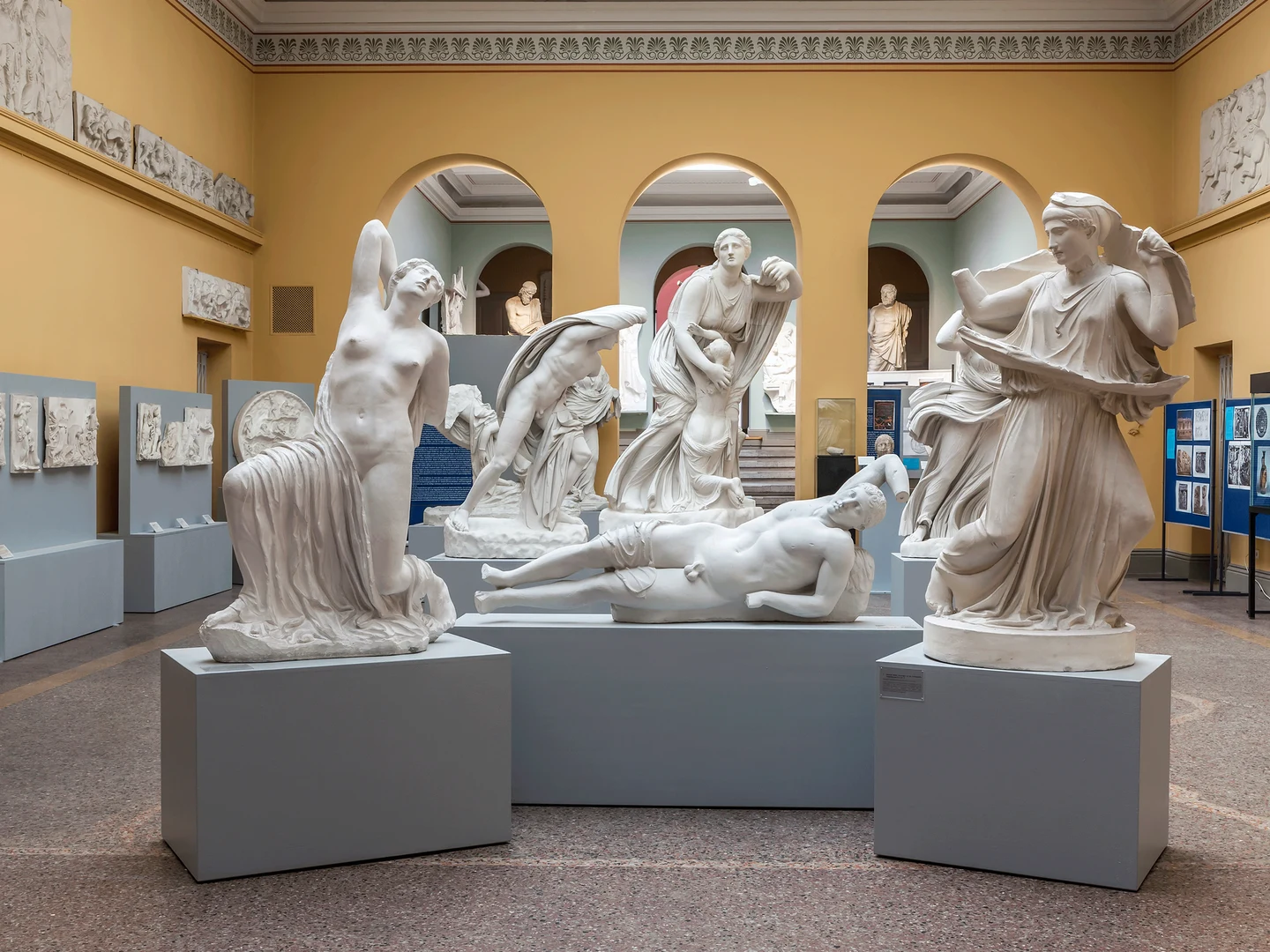 Eine Wissenschaftlerin und ein Wissenschaftler arbeiten hinter einer Glasfassade und mischen Chemikalien mit Großgeräten.