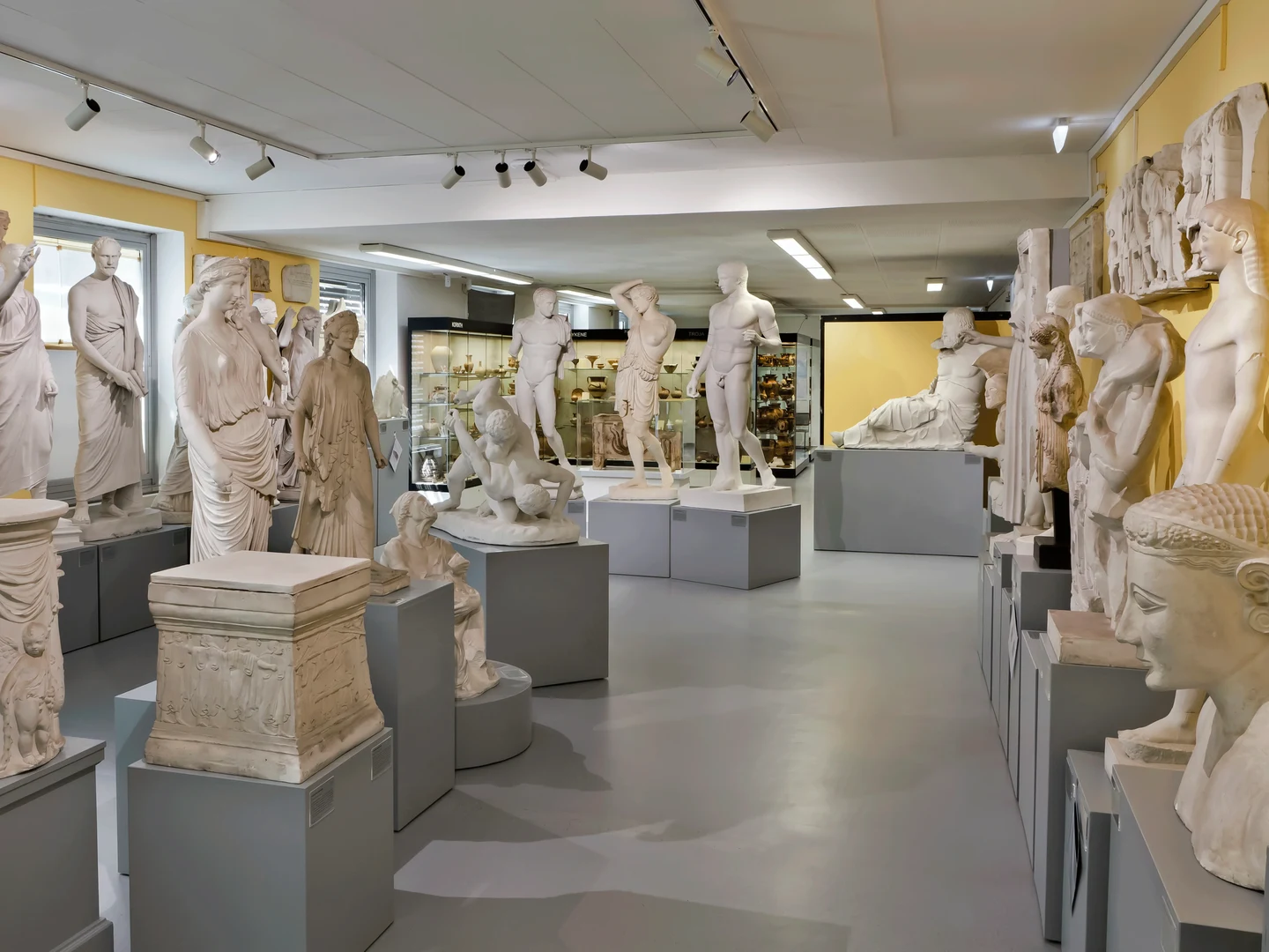 Eine Wissenschaftlerin und ein Wissenschaftler arbeiten hinter einer Glasfassade und mischen Chemikalien mit Großgeräten.