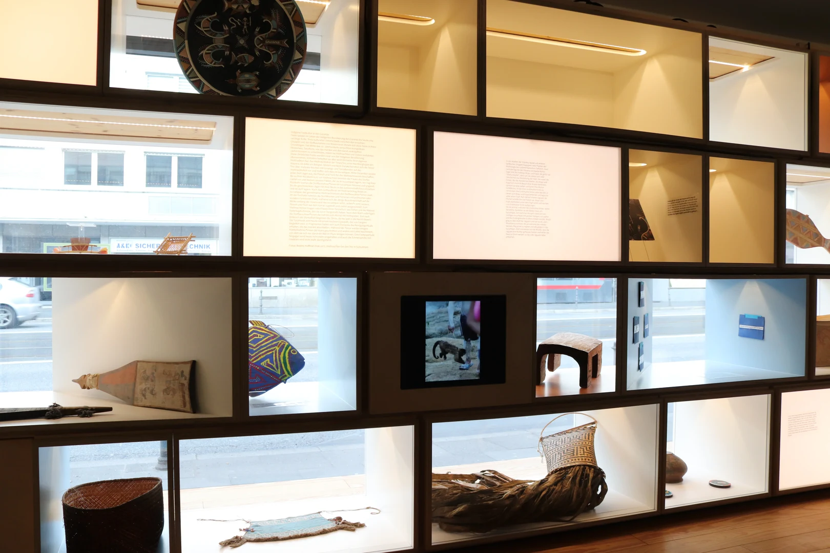 Eine Wissenschaftlerin und ein Wissenschaftler arbeiten hinter einer Glasfassade und mischen Chemikalien mit Großgeräten.